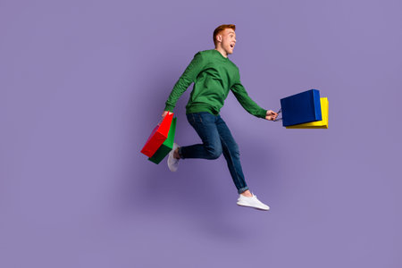Full length profile side photo of young man jump go walk hold shopping bag isolated over violet...