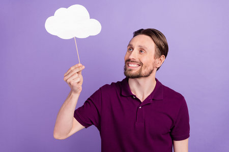 Photo of young cheerful man hold paper stick cloud plan rainy weather isolated over violet color backgroundの写真素材
