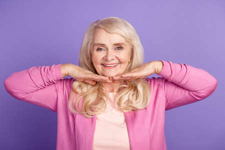 Photo of mature woman hands touch chin plastic surgery collagen lifting isolated over purple color backgroundの写真素材