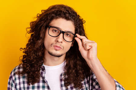 Photo of young serius guy hand touch eyeglasses confident clever isolated over yellow color backgroundの写真素材