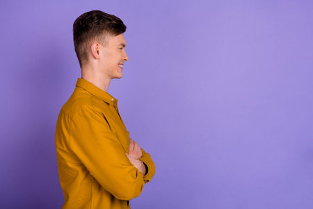 Profile side photo of young handsome cheerful man folded hands look empty space isolated over violet...