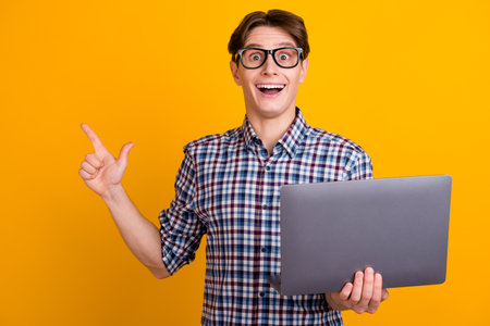 Portrait of attractive cheerful smart brunet guy agent broker hold hands laptop work isolated over bright color backgroundの写真素材