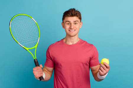 Photo of young man hold raquet play tennis exercise match competition isolated over blue color backgroundの写真素材