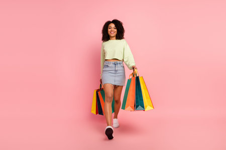 Full length photo of young adorable girl walk shopping buy gift new collection isolated over pink...