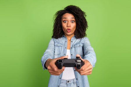 Photo of young pretty lady play game joystick station free time competition isolated over green...