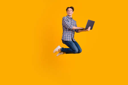 Full size photo of man jump use laptop search social media discounts isolated over bright color backgroundの写真素材