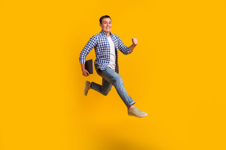 Full size photo of man jump run fast hold computer wear modern trendy outfit isolated over bright...