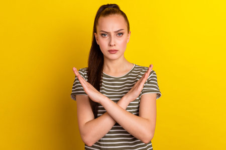 Confident young woman is showing no sign with crossed hands studio shot on vibrant color background.