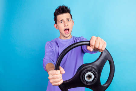 Photo of scared amazed blond hair man hold wheel isolated on blue color backgroundの写真素材