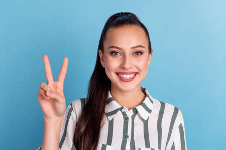 Portrait of cute sweet nice lady with her brunette hairstyle she give v-sign make white smile isolated on blue backgroundの写真素材