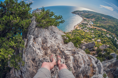high view from the rocks to the coast and juniper bushes, first-person, with legs in the frame, fish eye distortionの写真素材