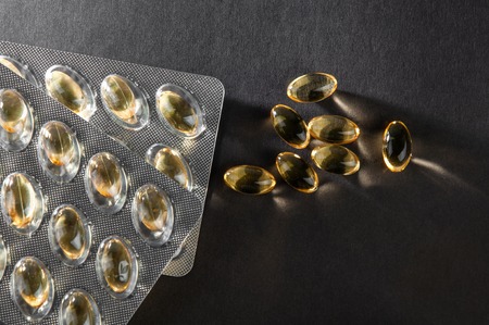 omega 3, fish oil capsules and blister on a dark background close up, top view, copy spaceの写真素材