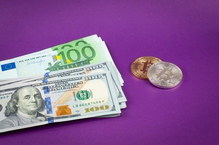 Bitcoins are on a purple background with dollars and euro close-up, some cash savingsの写真素材