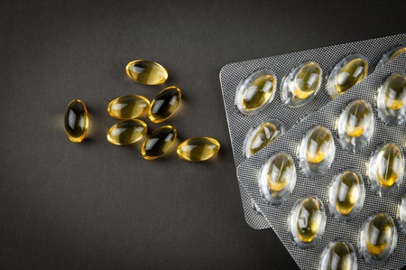 fish oil capsules omega3 and blister on a dark background close-up, top view, copy space, biologically active additiveの写真素材