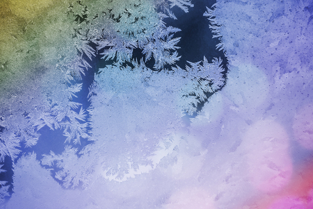 Frost and ice on the window. Glare through the glass. Festive background with a winter theme. bokeh blurred abstract colorful backgroundの写真素材