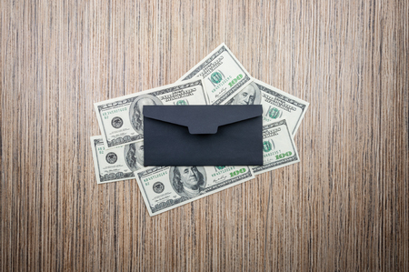 Dollars banknotes with black envelope on a wooden table. top viewの写真素材