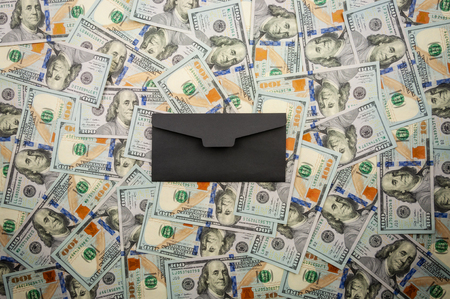 Black envelope on the background of banknotes of dollars. top viewの写真素材