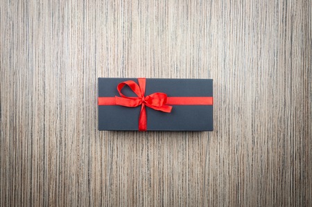 Black matte gift boxes with a bow on a wooden tableの写真素材
