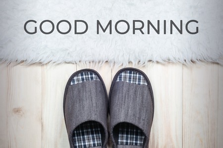 Textile slippers on a wooden floor with a white fur rug. Good morning concept.の写真素材