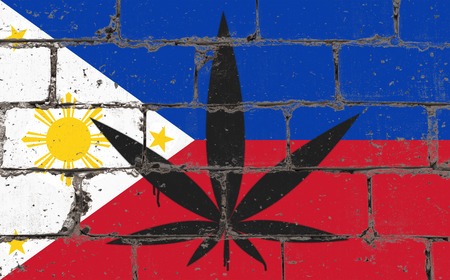 Graffiti street art spray drawing on stencil. Cannabis leaf symbol on brick wall with flag Philippinesの写真素材