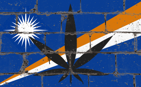 Graffiti street art spray drawing on stencil. Cannabis leaf symbol on brick wall with flag Marshall Islandsの写真素材