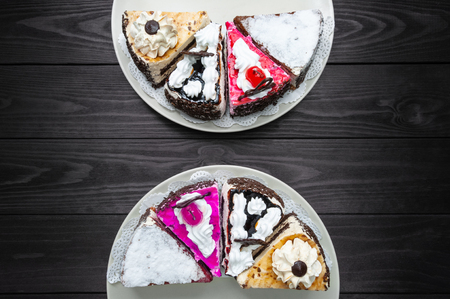 Various pieces of cake on plates on a dark wood background. top viewの写真素材