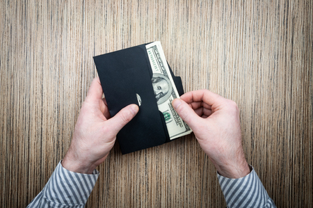 investing money dollars in an envelope with male hands on a wooden background. top viewの写真素材