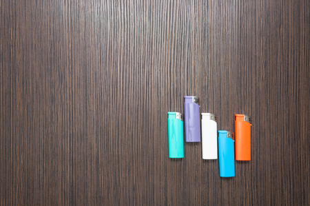 Multicolored lighters on a dark wooden table. top viewの写真素材