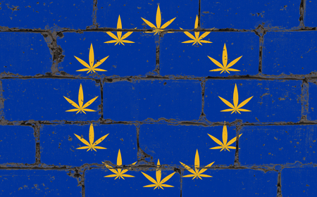 Graffiti street art spray drawing on stencil. Cannabis leaf symbol on brick wall with flag European Unionの写真素材