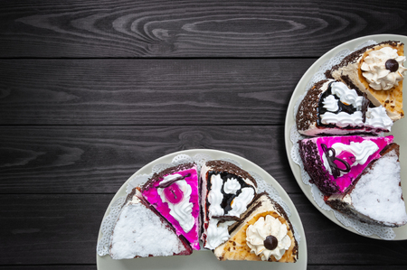 Various pieces of cake on plates on a dark wood background. top viewの写真素材