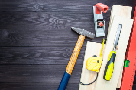 Carpentry tools and boards on a dark workbench. top view. copy space