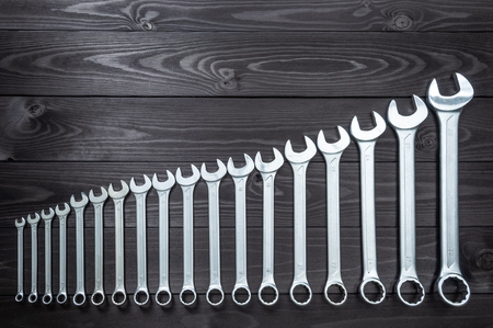 A set of new chrome wrenches on a dark wooden workbench. top view, copy spaceの写真素材