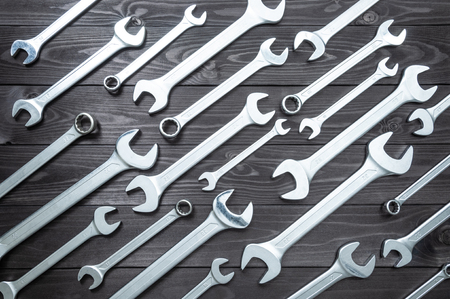 A set of new chrome wrenches on a dark wooden workbench. top viewの写真素材