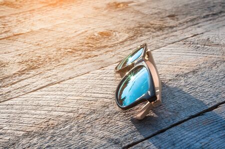 fashionable blue sunglasses on a natural wooden background, with sun highlightsの写真素材