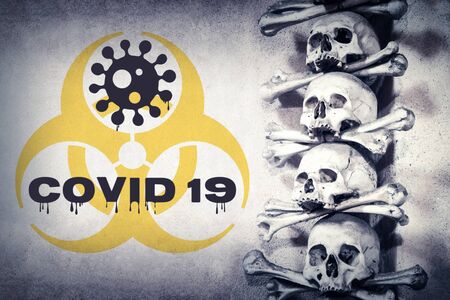 Concept COVID-19 coronavirus pandemic and death. COVID 19 text with symbol biohazard in photo of human skulls and bones.の写真素材