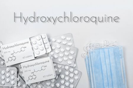 Hydroxychloroquine as possible treatment for coronavirus. Concept a tablets in boxes and blister with medical masks on white background. top viewの写真素材