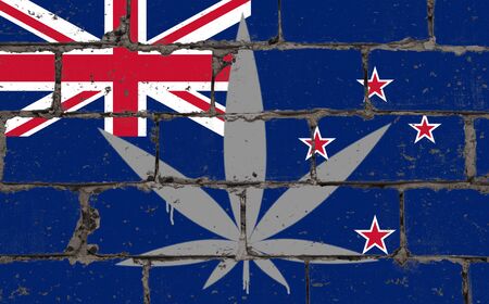 Graffiti street art spray drawing on stencil. Cannabis leaf symbol on brick wall with flag New Zealandの写真素材