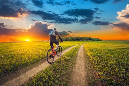 Ride of the bike on a dirt road in a field at sunset.の写真素材