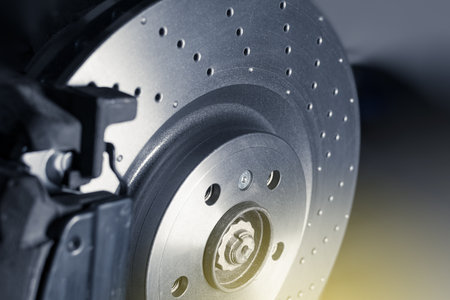 Installation of new perforated brake discs and pads on a modern auto in the car workshop. Close up. Blur effect.の写真素材