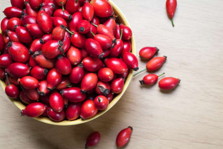 closeup photo of a yellow bowl full of rosehip berriesの写真素材