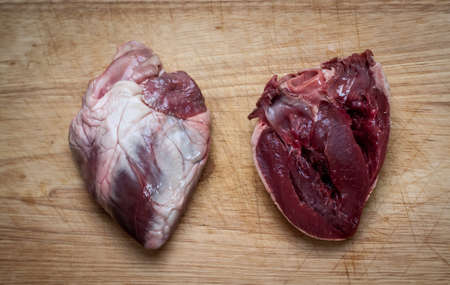 closeup photo of a whole and a cut lamb heart on a chopping boardの写真素材