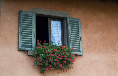 closeup photo of a traditional Italian window decorated with flowersの写真素材