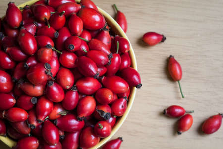 closeup photo of a yellow bowl full of rosehip berriesの写真素材