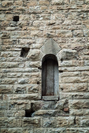 closeup photo of a narrow window on a stone wall in Italyの写真素材