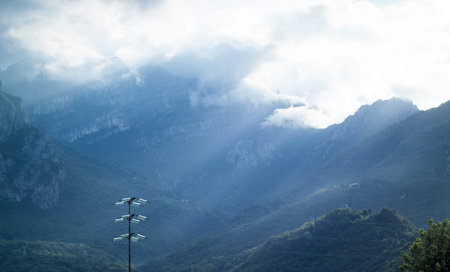 dramatic light falling from the sky in Italy, with a shiny utility pole in the foregroundの写真素材