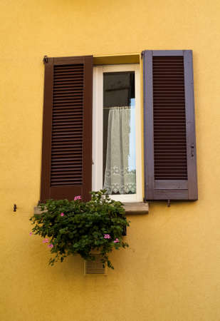 closeup of a traditional Italian window on a bright yellow wallの写真素材