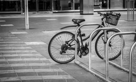 a black-and-white photo of a lonely bicycle parked in a desolate streetの写真素材