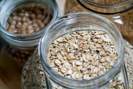 closeup photo of a glass jar full of porridge flakes, with some rice and chickpeas in the background
