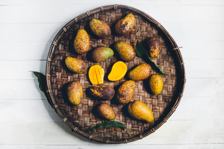 Nature mango In threshing basket On a wooden table and a white clothの写真素材