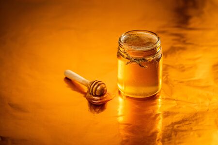Golden honey in a glass bottle and golden background,Honey scoopの写真素材